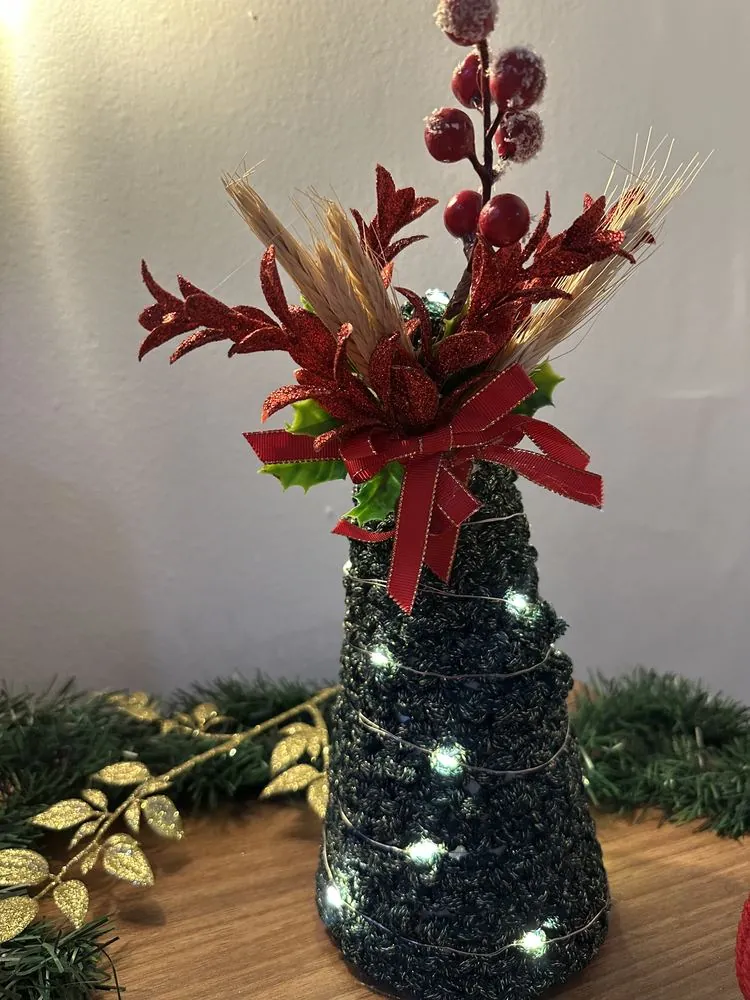 Árvore de Natal de macramê verde com luzinhas e arranjo vermelho