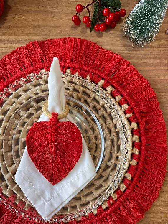 Porta-guardanapo vermelho de macramê sobre sousplat de palha com franja vermelha